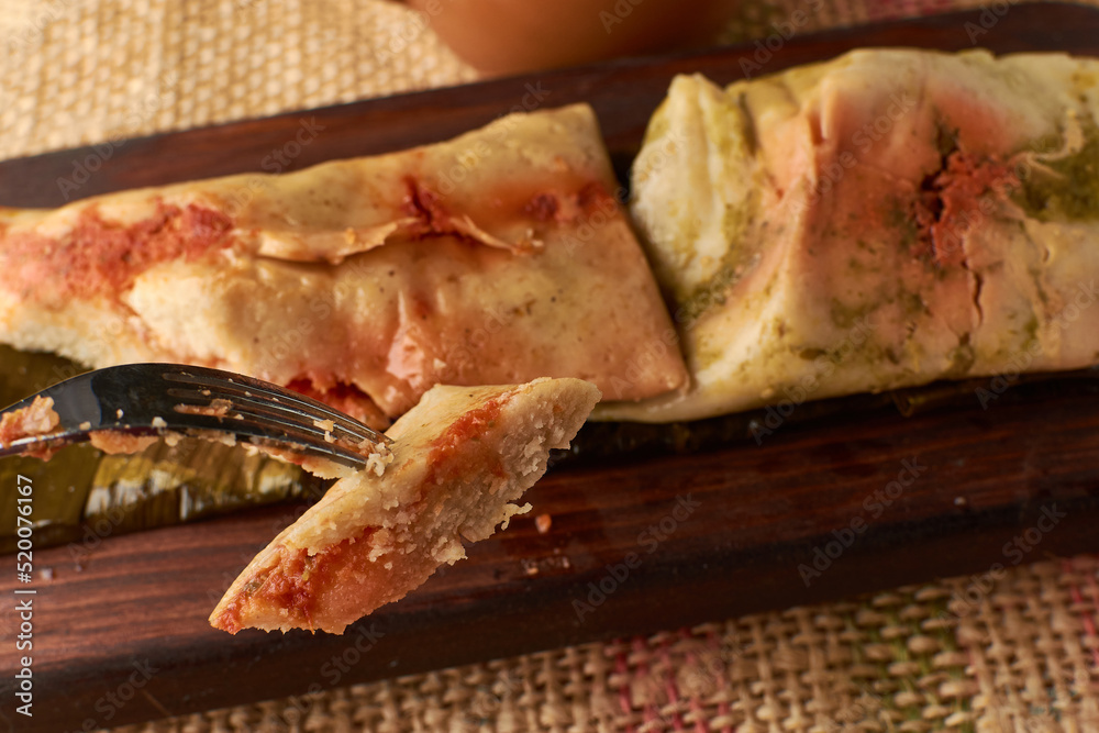 Ranchero tamales with red and green sauce placed on their banana leaf