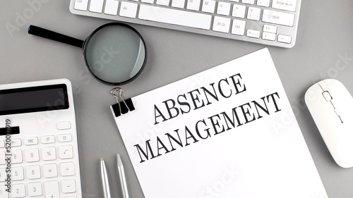 Fotografija ABSENCE management written on paper with office tools and keyboard on the grey b