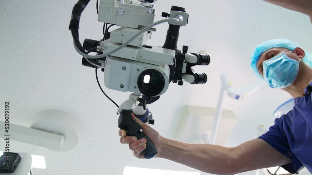 Professional surgeon places the powerful microscope over the camera. Light blinding the view. Low angle shot. Professional surgeon places the powerful microscope over the camera. Light blinding the view. Low angle shot.