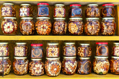 Jars of sweets with fresh honey and nuts in selective focus are sold at an outdoor farmers market. Agricultural honey fair. Sale of healthy and wholesome food.