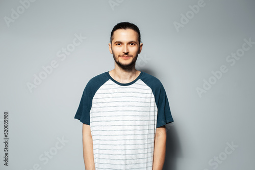 Studio portrait of serious guy on grey background, wearing white shirt with blue. © Lalandrew