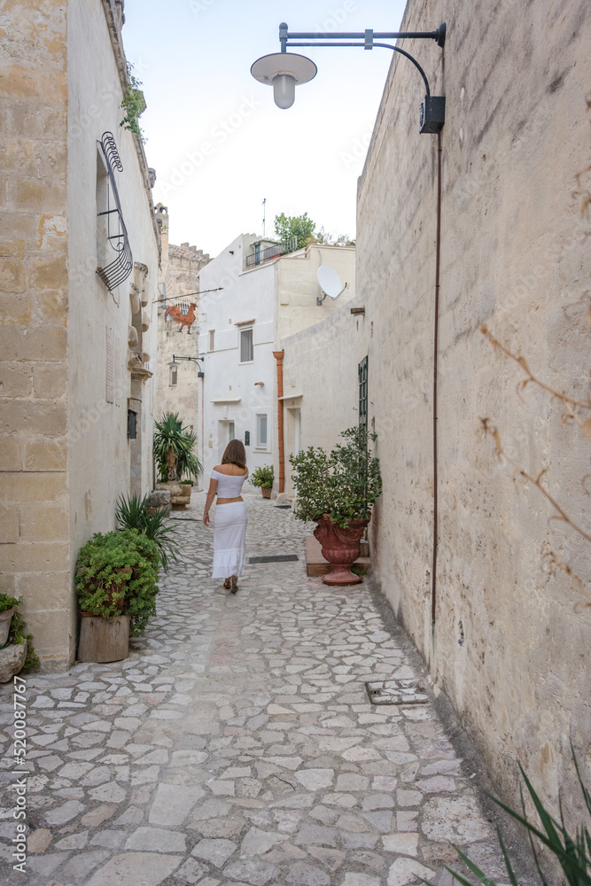 Portrait of a young and beautiful girl walking with her back turned in the alleys of the old town center of an ancient city