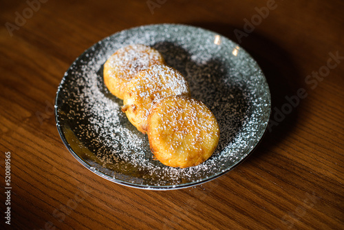 dish of sweet cheese pancakes on brown wooden background photo