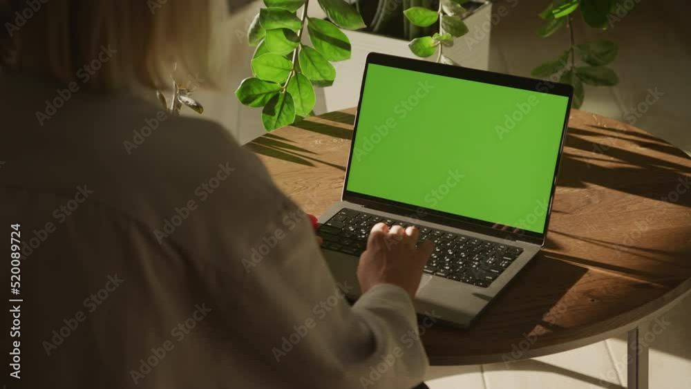 Handheld shot of a caucasian woman hand scrolling and pressing enter on a laptop with green screen