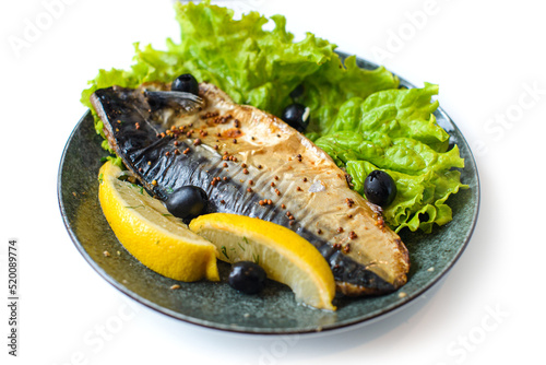 mackerel baked in french mustard sauce with slice of lemon, lettuce and olives on plate on white background photo