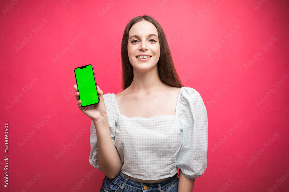 Happy woman standing and hold smartphone on pink background. Green screen phone screen Happy woman standing and hold smartphone on pink background. Green screen phone screen