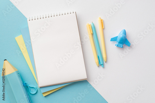 School supplies concept. Top view photo of yellow and blue school accessories notebooks plane shaped sharpener pens and pencil-case on bicolor blue and white background with copyspace