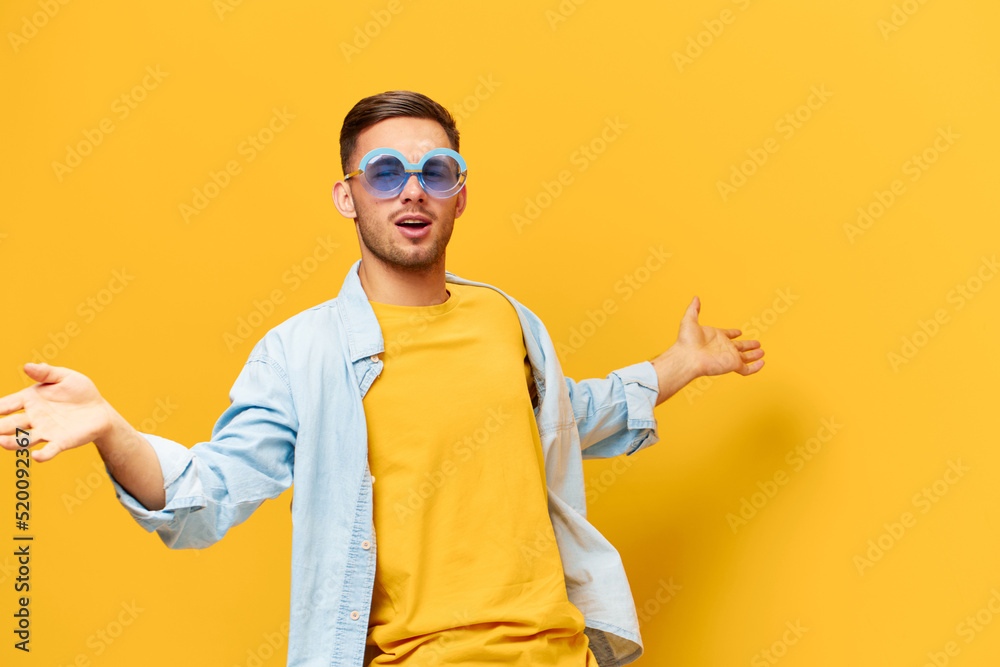 Dancing joyful tanned handsome man in blue shirt trendy sunglasses raise hands up posing isolated on orange yellow studio background. Copy space Banner Mockup. Relax time Party concept
