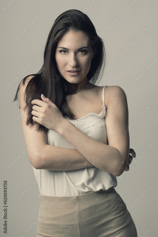 Fashion, style, beauty and make-up concept. Beautiful woman fashion studio portrait with long dark hair and day make-up with seductive look and pose with crossed arms. Toned image with beige color Fashion, style, beauty and make-up concept. Beautiful woman fashion studio portrait with long dark hair and day make-up with seductive look and pose with crossed arms. Toned image with beige color