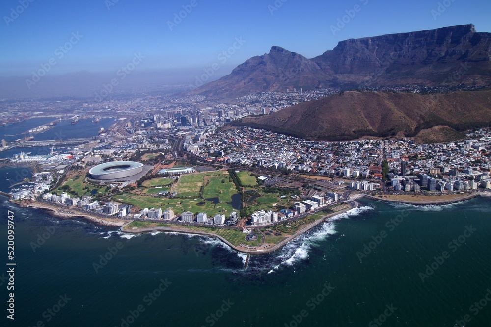 aerial view over Cape Town with sea point coastline and stadium in foreground and city, harbour and table mountain in background