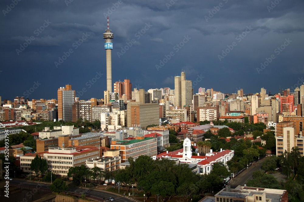 Naklejka premium overview over downtown of Johannesburg with TV-tower and dark thunder clouds with sun