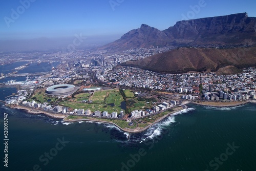 aerial view over Cape Town with sea point coastline and stadium in foreground and city, harbour and table mountain in background