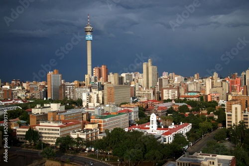 overview over downtown of Johannesburg with TV-tower and dark thunder clouds with sun