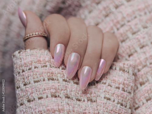 Beautiful pink nail manicure. Stylish pastel pink manicure. Nail polish. Art pink manicure. Female hands manicure close up view on pink knitted blzer background. photo