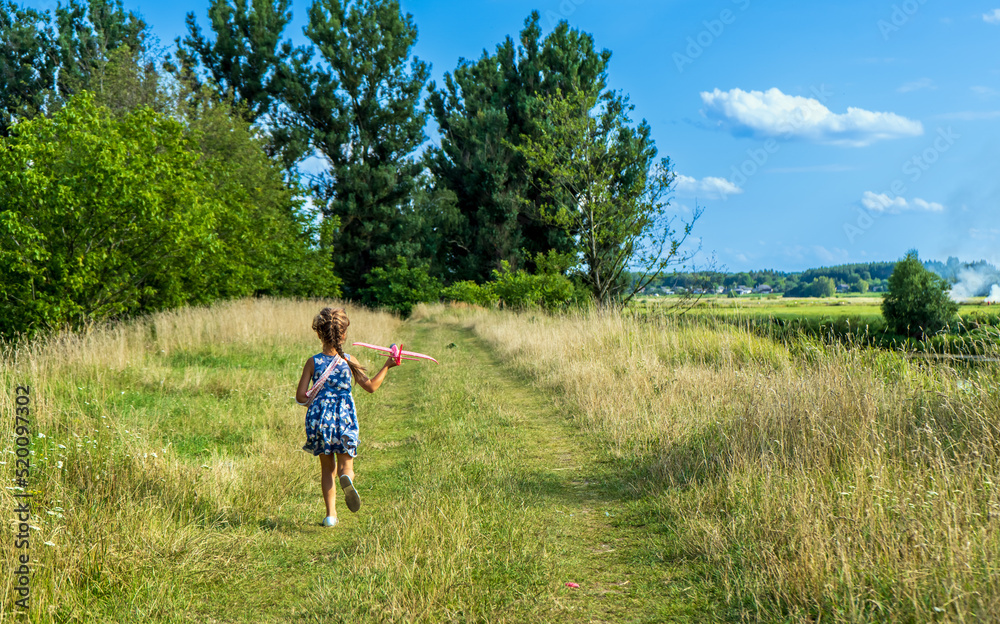 Beautiful little girl, run on the grass and launches a red toy plane. Little kid having fun during summer holidays. Childhood and travel vacation concept. Beautiful little girl, run on the grass and launches a red toy plane. Little kid having fun during summer holidays. Childhood and travel vacation concept.
