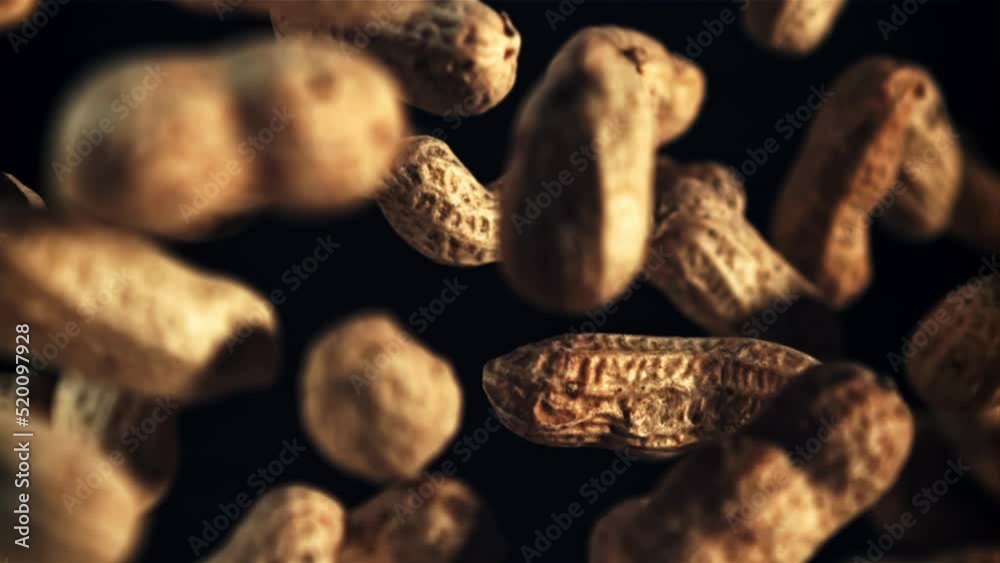 Peanuts in the shell fly up and rotate in flight. On a black background. Top view. Filmed is slow motion 1000 fps.