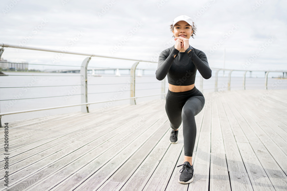 A woman does fitness exercises, uses a tracker on her hand, a smart watch for sports, training in sportswear