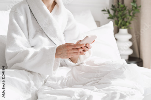 Woman in bathrobe using online app on her smartphone