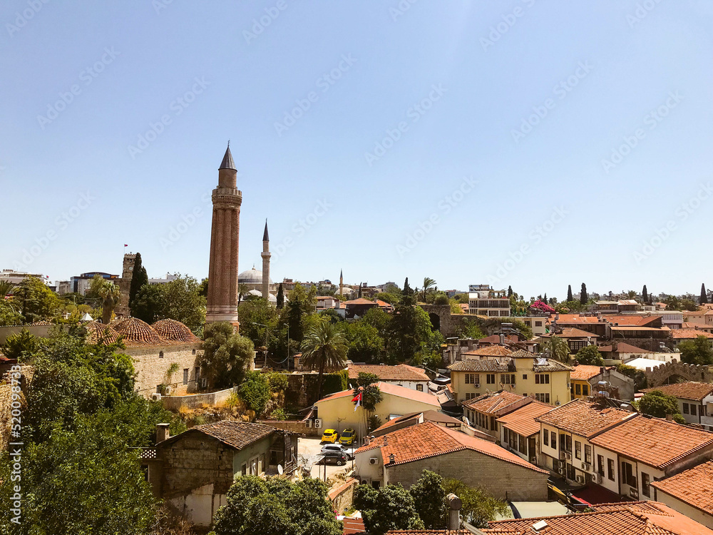 view of the city from above. houses with brown, brick roof. life in a tropical, warm country. travel to the sea, vacation. on the square stands a tower with a sharp spire