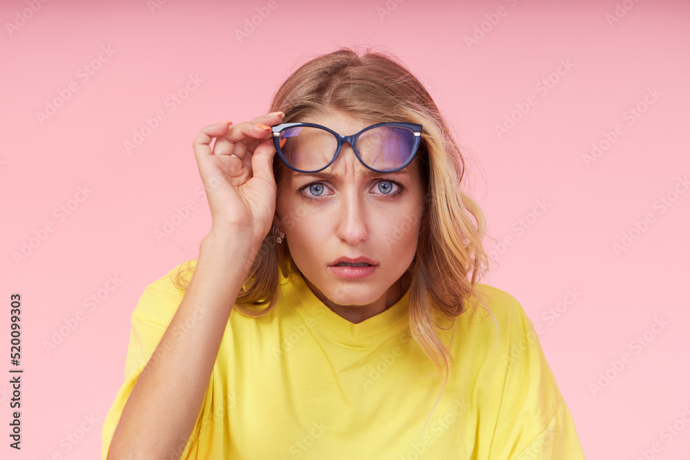 Portrait of young excited woman in glasses, yellow casual t-shirt on pink background. Surprised and incredulous looks wide open mouth and eyes Portrait of young excited woman in glasses, yellow casual t-shirt on pink background. Surprised and incredulous looks wide open mouth and eyes