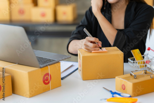 Startup SME small business entrepreneur woman using phone call receive from customer checking product on stock at home office, online marketing packaging delivery box, SME e-commerce concept. © crizzystudio