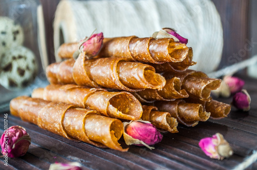 Homemade apple leather rolls and candied fruit on the wooden table.