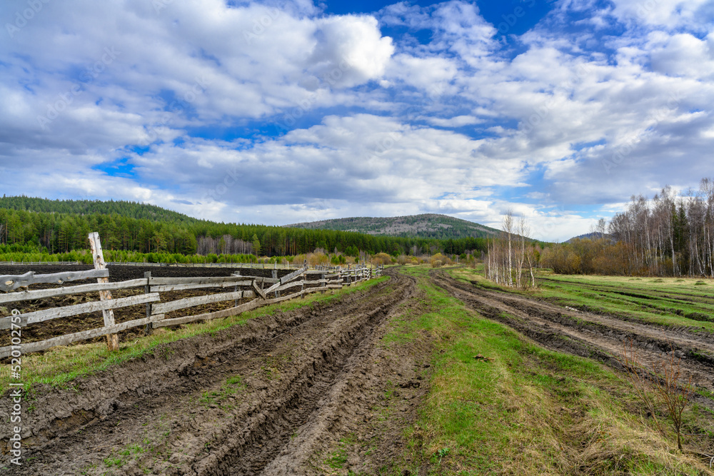 Obraz premium South Ural farm, wooden fence and arable land with a unique landscape, vegetation and diversity of nature.