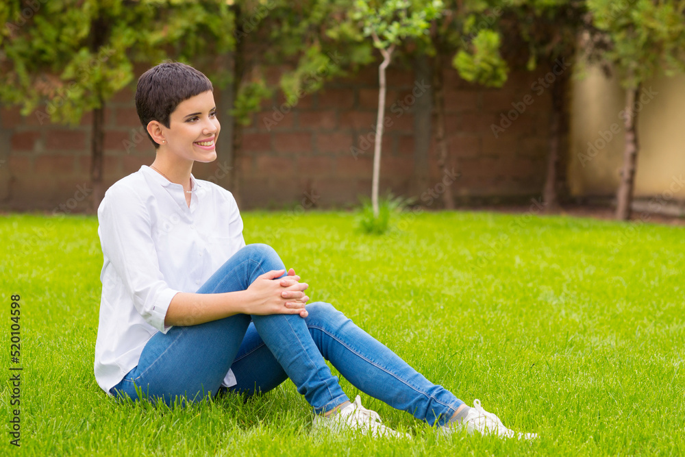 Young woman sitting on the beautiful grass in spring Young woman sitting on the beautiful grass in spring