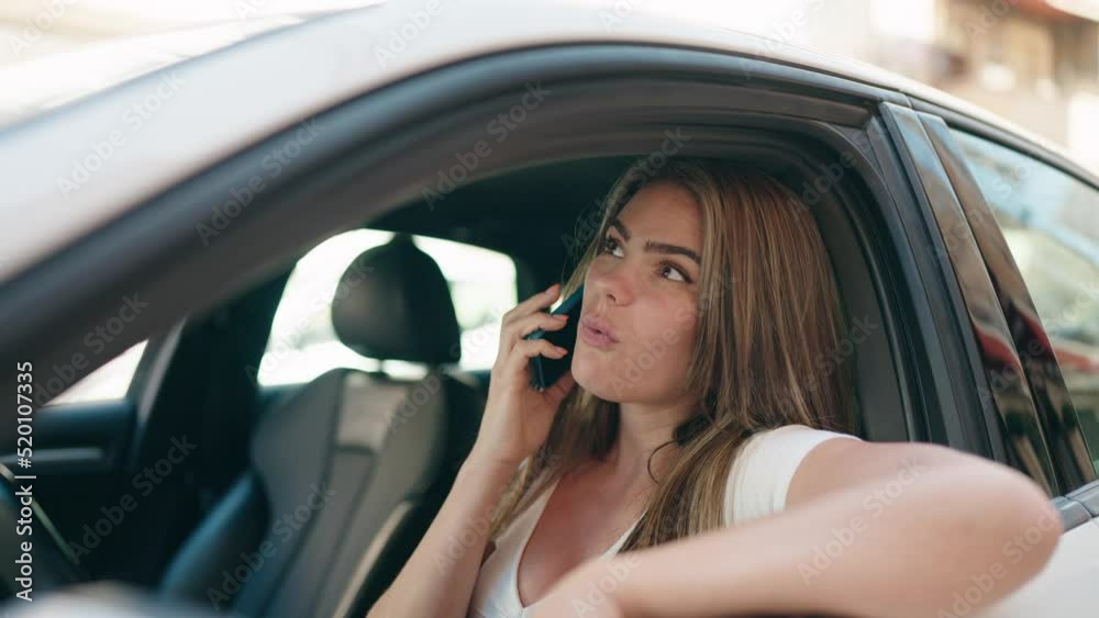 Young woman talking on the smartphone sitting on car at street Young woman talking on the smartphone sitting on car at street
