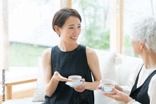 リビングでお茶を飲む笑顔の親子（ミドル・シニア・女性・母子・嫁・姑） photo