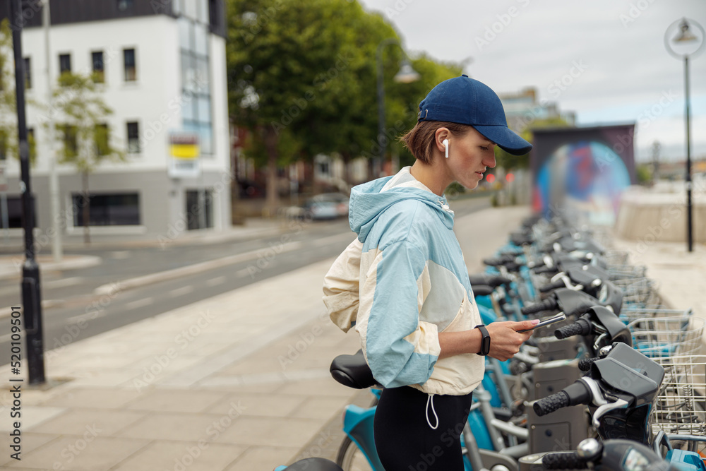 Young sportive woman renting bicycle in bike sharing city service
