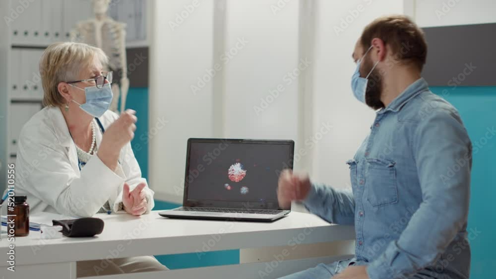 Physician analyzing virus animation on laptop with sick patient during covid 19 pandemic in checkup cabinet. Examination of coronavirus illustration for prevention and recovery on computer. Physician analyzing virus animation on laptop with sick patient during covid 19 pandemic in checkup cabinet. Examination of coronavirus illustration for prevention and recovery on computer.