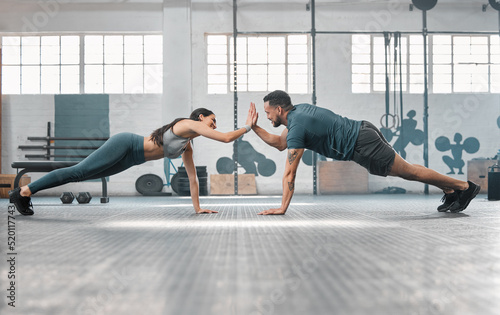 Fitness partners exercising together and doing pushups high five at the gym. Fit and active man and woman training in a health facility as part of their workout routine. A couple doing an exercise photo