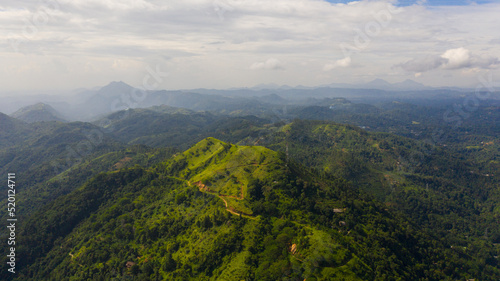 Mountain peaks covered with forest from above. Mountains covered rainforest  trees and blue sky with clouds. Sri Lanka.