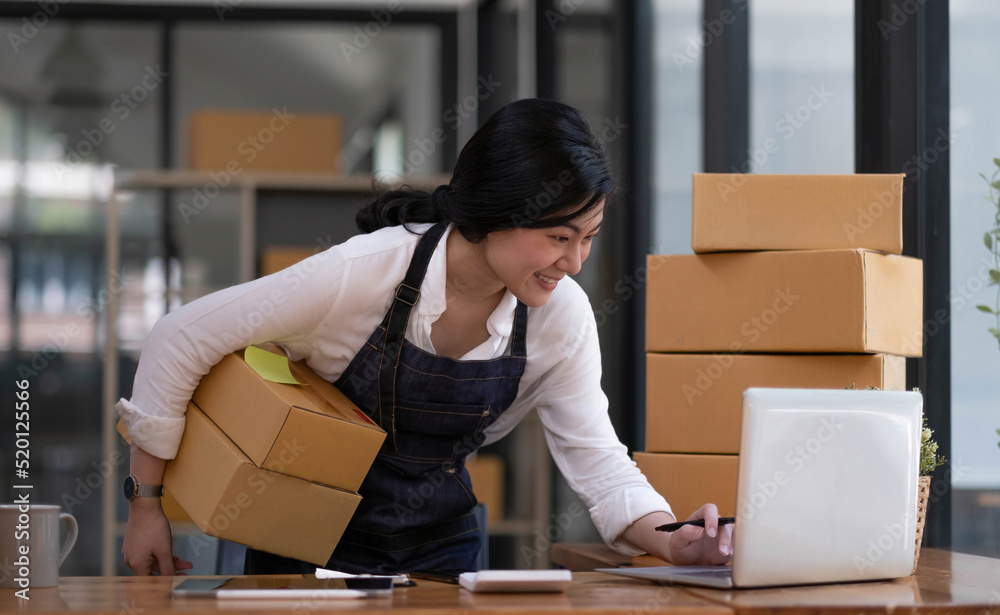 Startup SME small business entrepreneur SME or freelance Asian woman using a laptop with box, Young success Asian woman with her hand lift up, online marketing packaging box and delivery, SME concept. Startup SME small business entrepreneur SME or freelance Asian woman using a laptop with box, Young success Asian woman with her hand lift up, online marketing packaging box and delivery, SME concept.