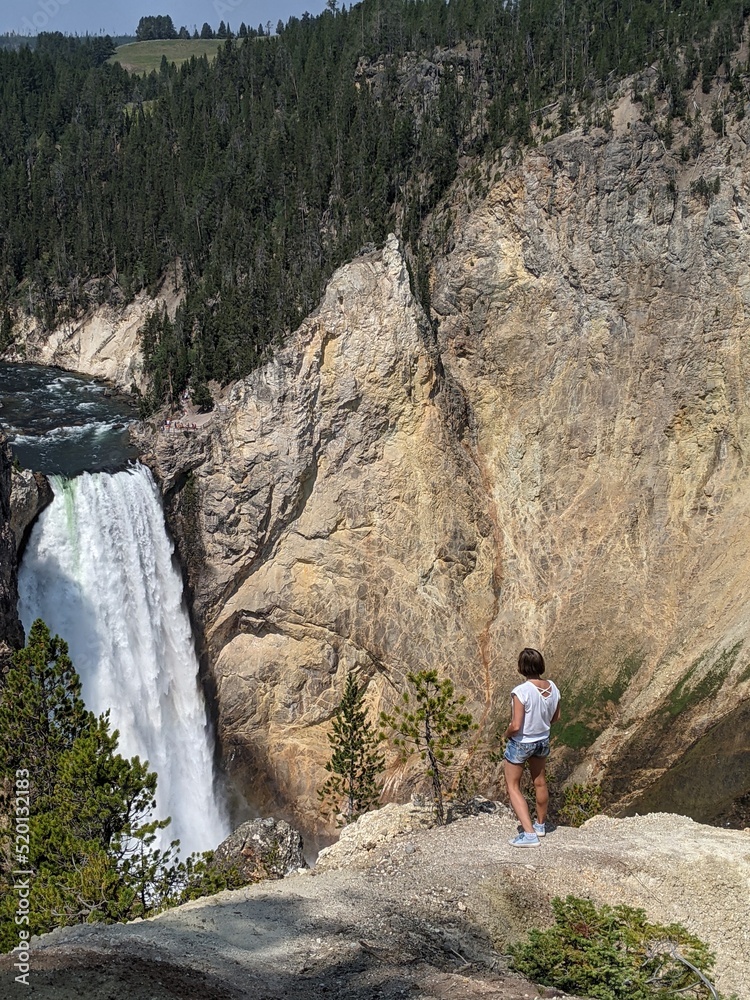 hiker in the mountains looking at waterfall in Yellowstone 