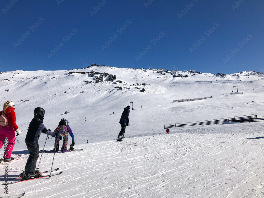 Skiiers and snowboarders beginning their descent down the snowy slopes at Thredbo