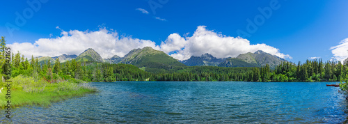 Fototapeta Naklejka Na Ścianę i Meble -  Scenic panorama over lake in park High Tatras. Strbske Pleso, Slovakia. Wonderful summer landscape. Picturesque view of nature. Amazing natural wide background, green forest, blue sunny sky clouds