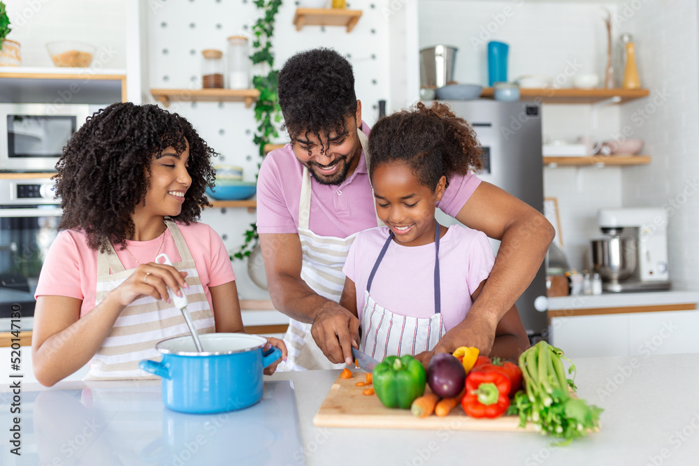 Kind african parents teaching their adorable daughter how to cook healthy food, free space