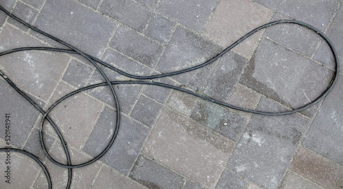 Electric wire lies on paving slabs.