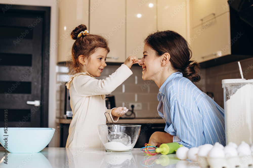 Mother with daughter having fun with flour at the kitchen Mother with daughter having fun with flour at the kitchen