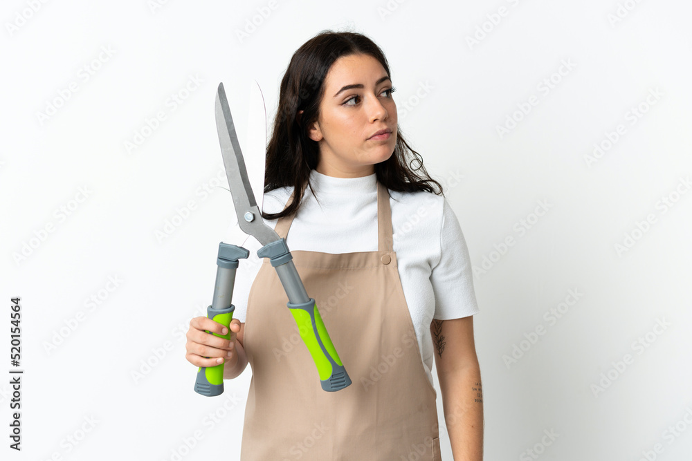 Young caucasian woman holding a plant isolated on white background looking to the side