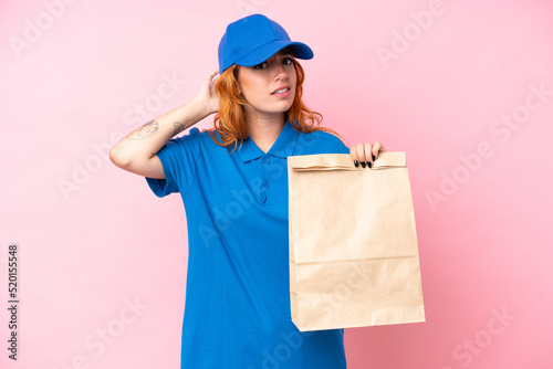 Young caucasian woman taking a bag of takeaway food isolated on pink background having doubts