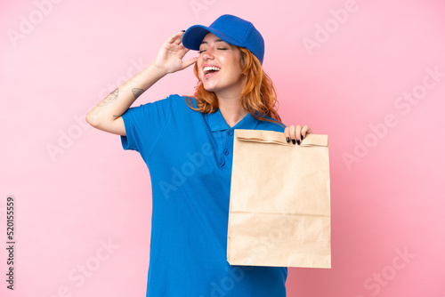 Young caucasian woman taking a bag of takeaway food isolated on pink background smiling a lot