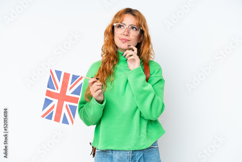 Young caucasian woman holding an United Kingdom flag isolated on white background having doubts and thinking