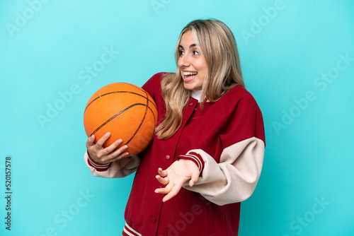 Young caucasian basketball player woman isolated on blue background with surprise expression while looking side