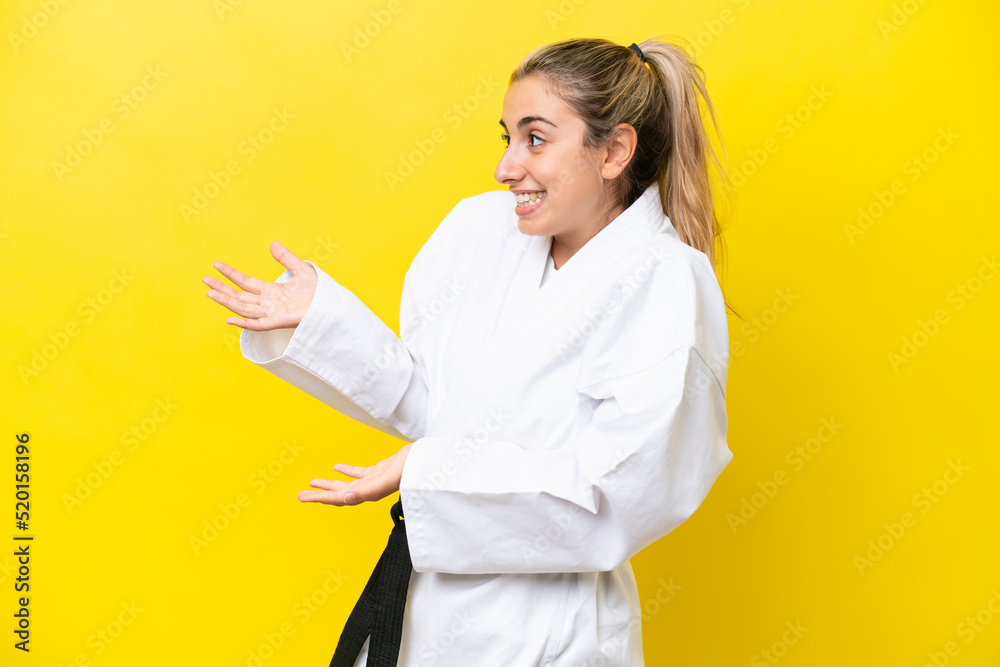 Young caucasian woman doing karate isolated on yellow background with surprise expression while looking side Young caucasian woman doing karate isolated on yellow background with surprise expression while looking side