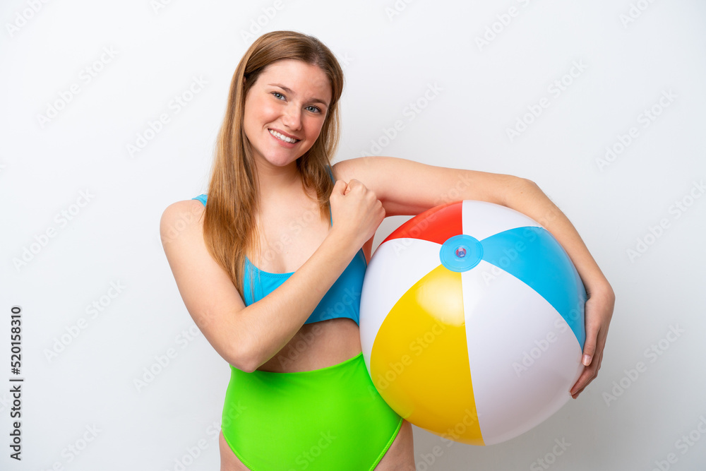 Young woman holding beach ball in holidays isolated on white background celebrating a victory Young woman holding beach ball in holidays isolated on white background celebrating a victory