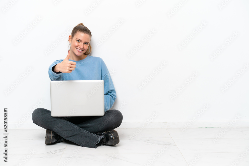 Young woman with a laptop sitting on the floor with thumbs up because something good has happened Young woman with a laptop sitting on the floor with thumbs up because something good has happened