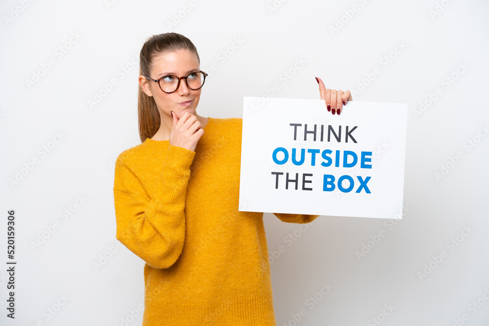 Young caucasian woman isolated on white background holding a placard with text Think Outside The Box and thinking Young caucasian woman isolated on white background holding a placard with text Think Outside The Box and thinking